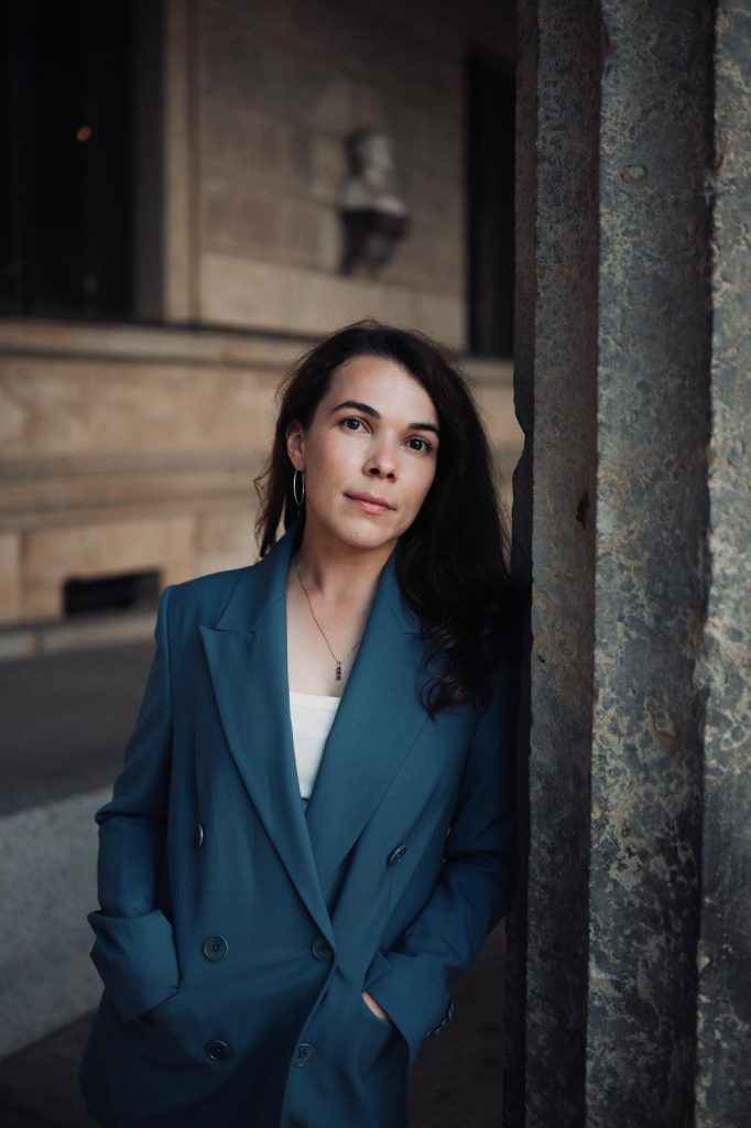 Petra Rațiu im blauen Blazer, an eine Säule in Hermannstadt gelehnt