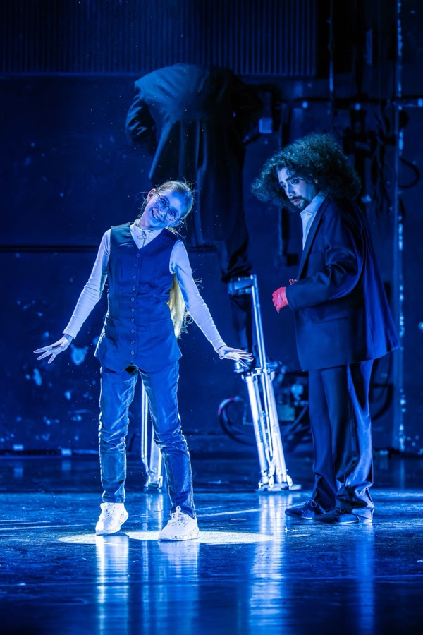 A girl and the dancer face each other in cold blue light.