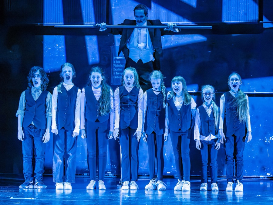 The children shout in chorus while the clown looms behind them.