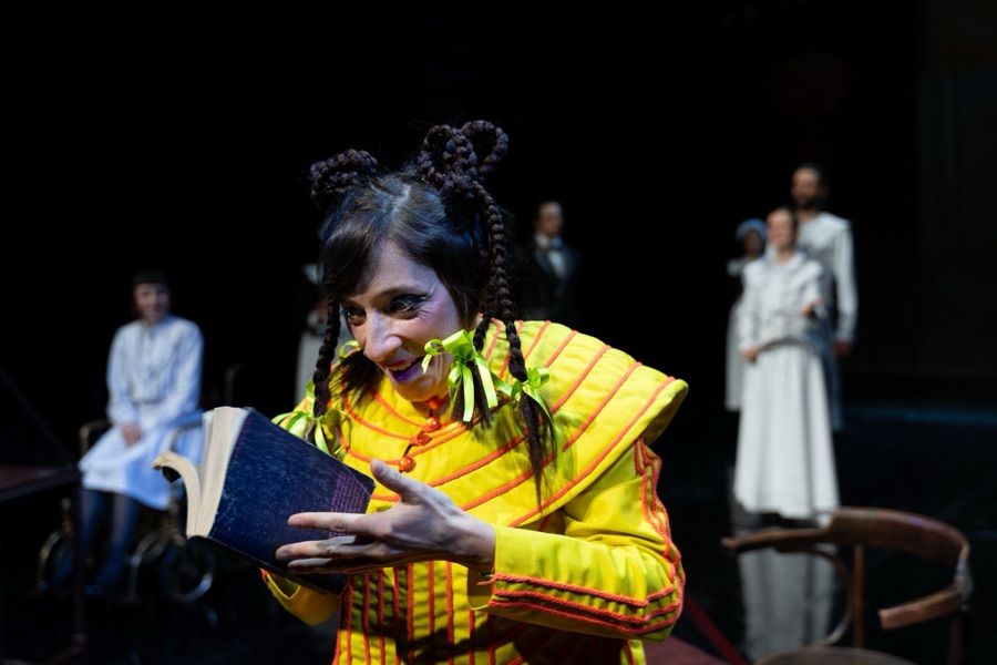Heidi, with braided horns of hair and green ribbons, laughs over an open book.