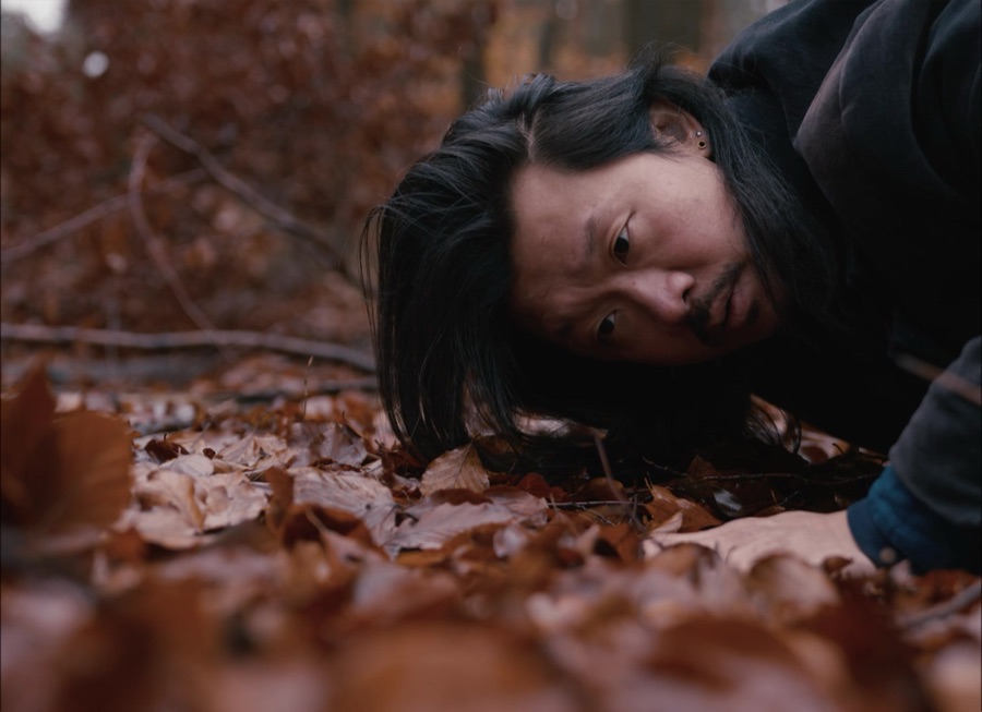 Ardian Hartono presses his face to the forest floor among red autumn leaves.