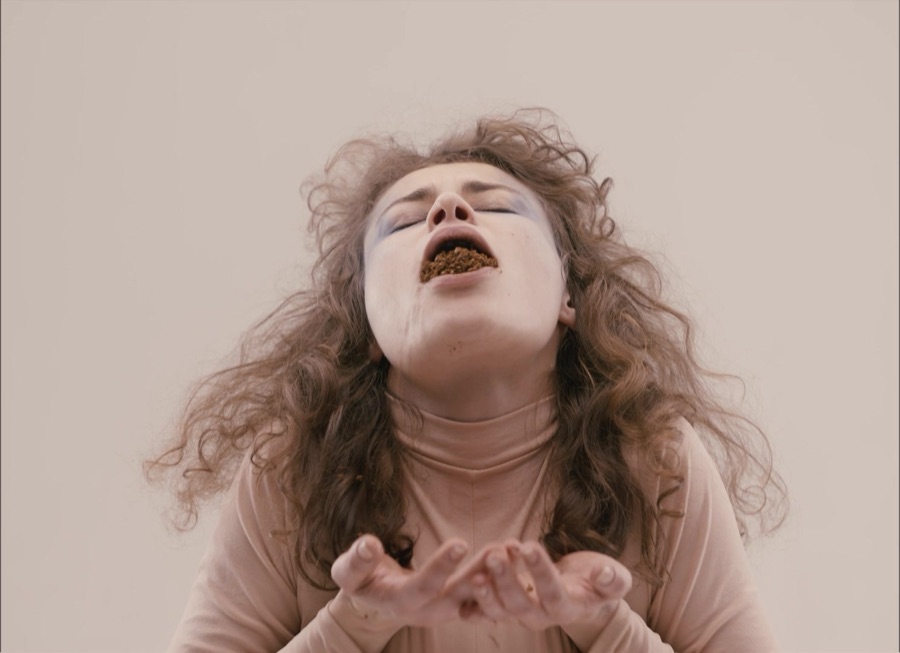 Eyes closed, mouth full of leaves, she holds out her open hands.