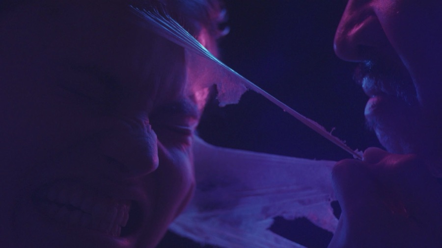 A translucent film stretches between their faces.