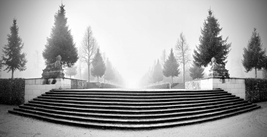Black-and-white wide view of the Sphinx staircase in the Rheinsberg Lustgarten in mist, the flyer motif and outdoor venue of the performance.